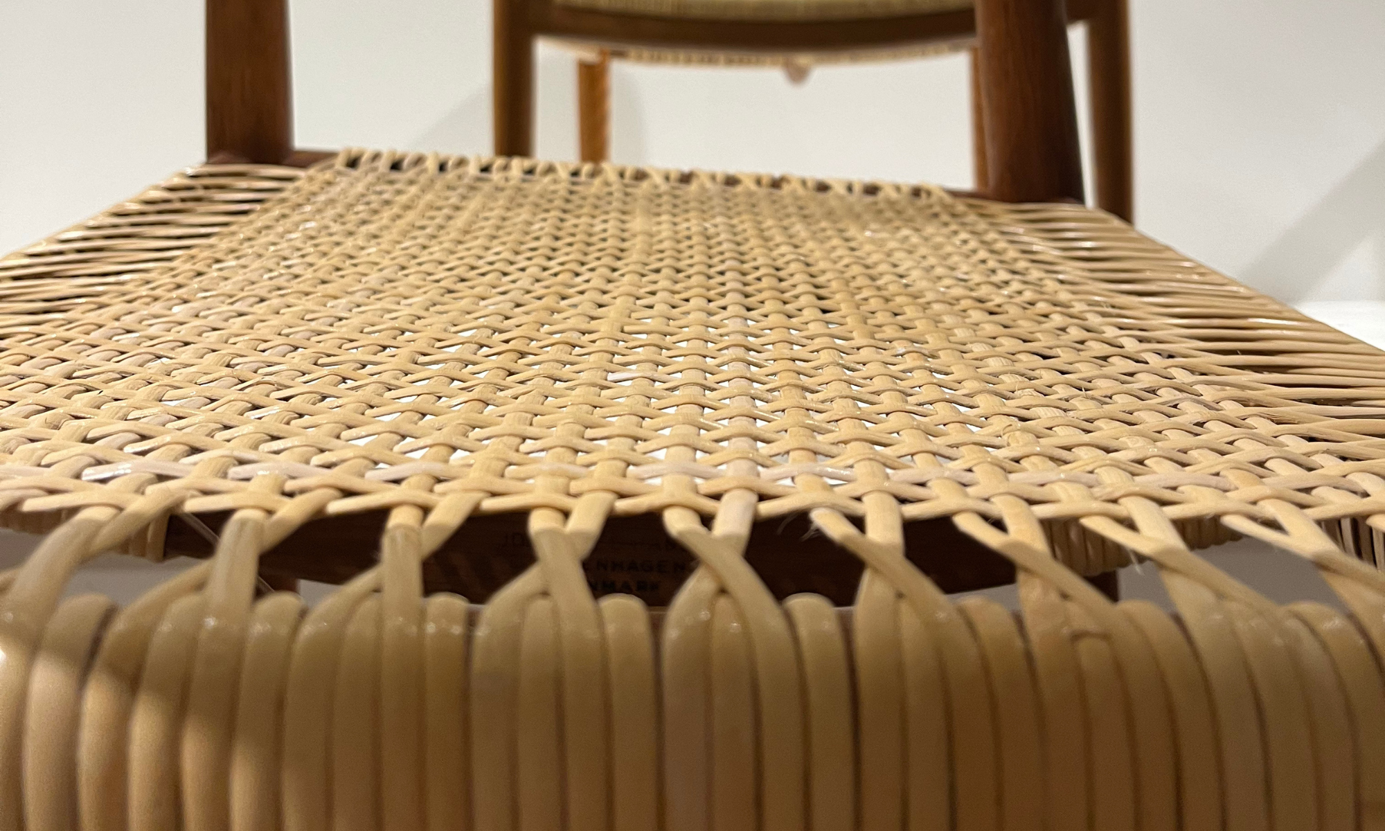 Sæde med klassisk sjeneflet i lyst rattan på dansk designerstol med stel i massivt træ.