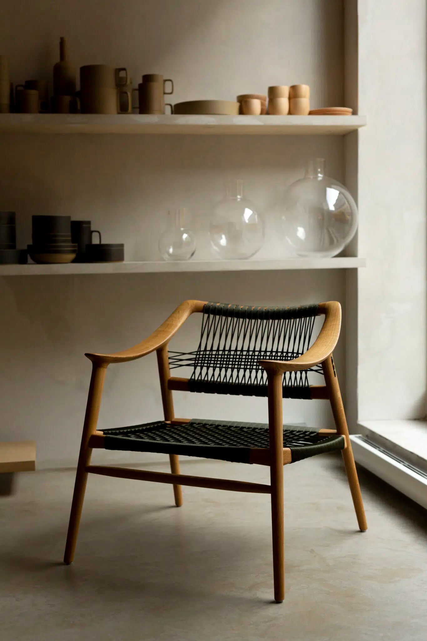 Bambi lounge stol i eg med sort flaglineflet på sæde og ryg, placeret i moderne interiør.