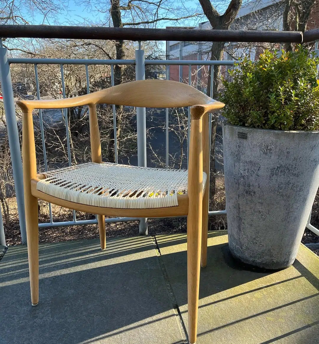 PP501 The Chair i lyst træ med flettet sæde og ryg, set fra skråt forfra på en altan.