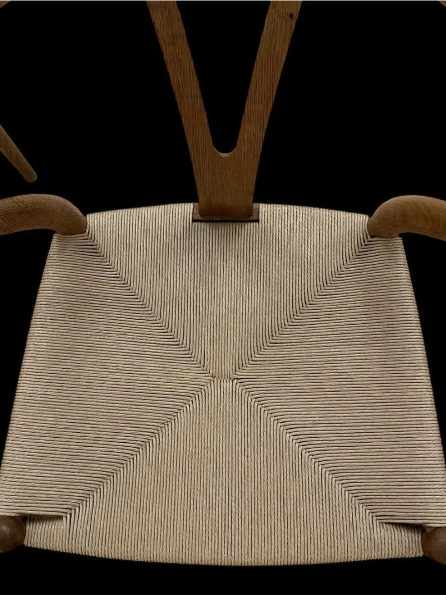 Nærbillede af kuvertflet i naturfarvet papirgarn på en Y-stol med ryglæn i olieret træ, designet af Hans J. Wegner.